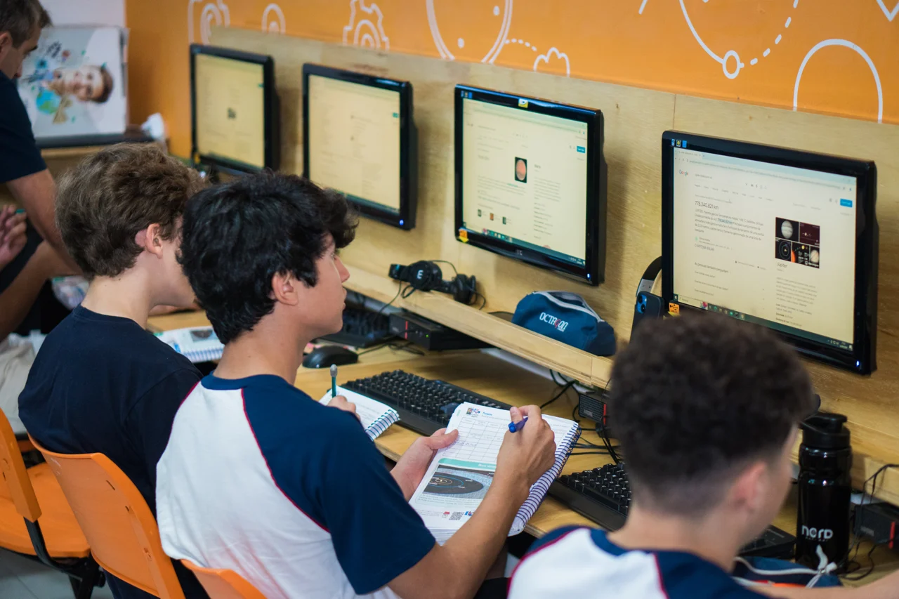 Alunos trabalhando com livros e computadores durante uma aula no Octagon